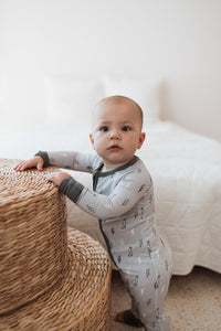 Baby står upp i grå pyjamas