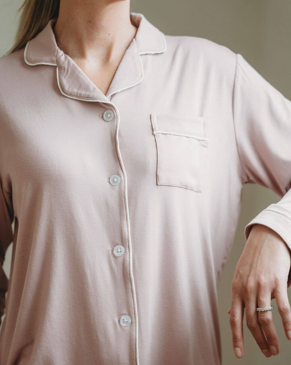 Person wearing a light pink button-up shirt against a neutral background