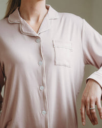 Person wearing a light pink button-up shirt against a neutral background