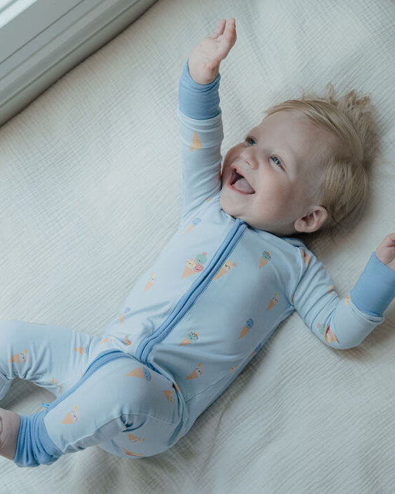 Child wearing a blue onesie with zippers on a white surface