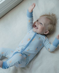 Child wearing a blue onesie with zippers on a white surface