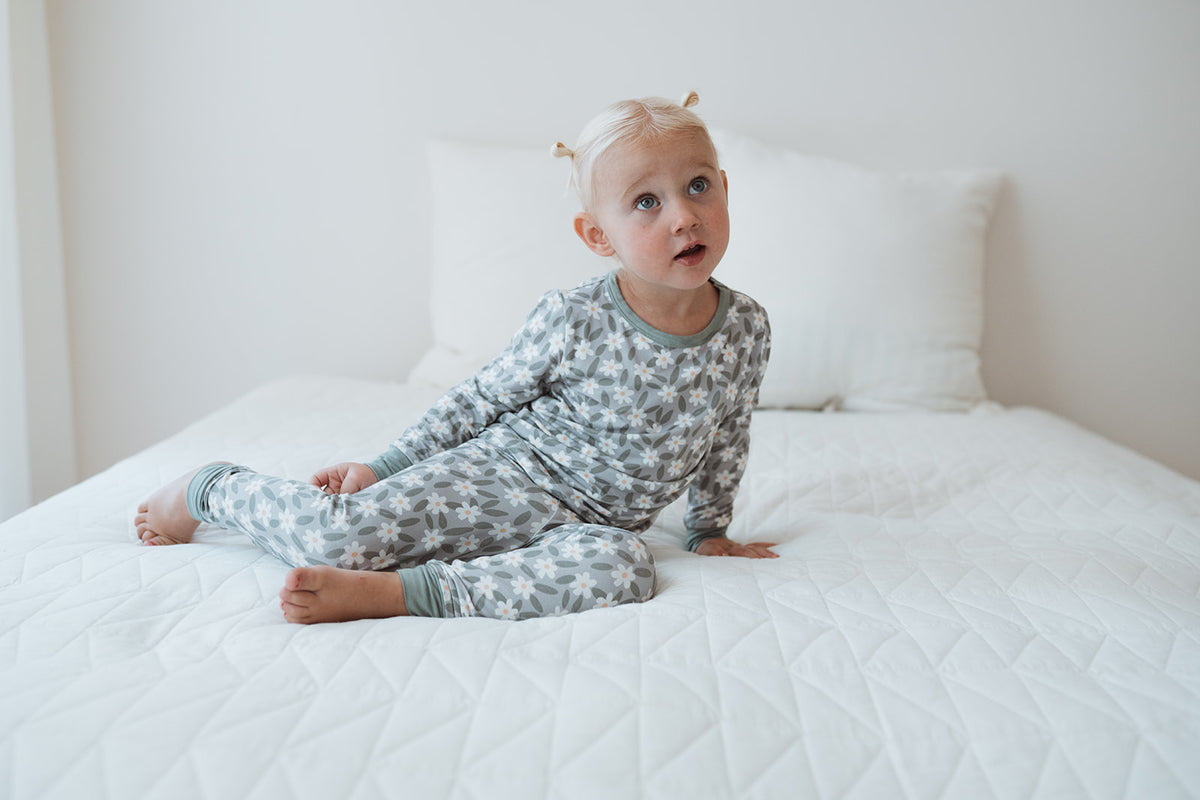 Söt flicka i sängen i sin gröna pyjamas med blommor