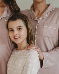 Two adults and a young girl wearing matching pajamas against a neutral background